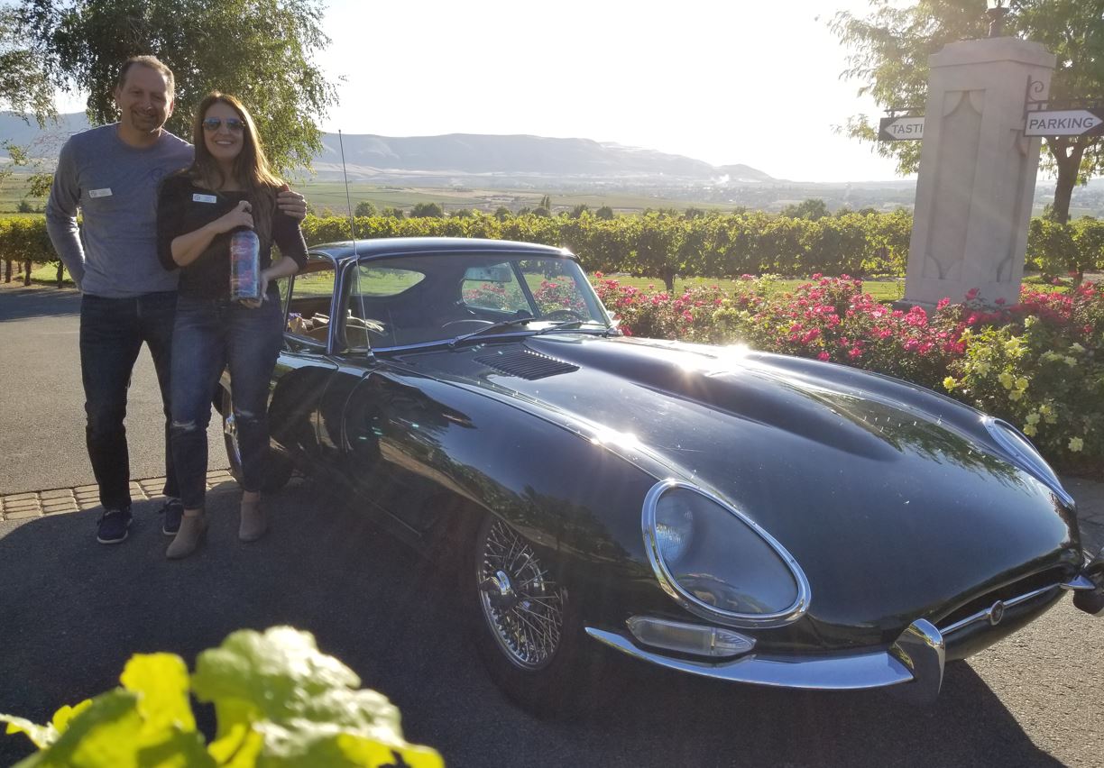 Ehab and Samah, posed in front of their E-Type, with their purchase of wine in a special bottle which was etched and painted.